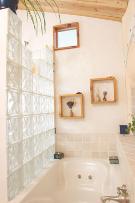The master bath’s jetted tub is nestled between a glass-block shower wall and a window overlooking the plains. Tiles above the window were hand cut and inset with iridescent accent tile.